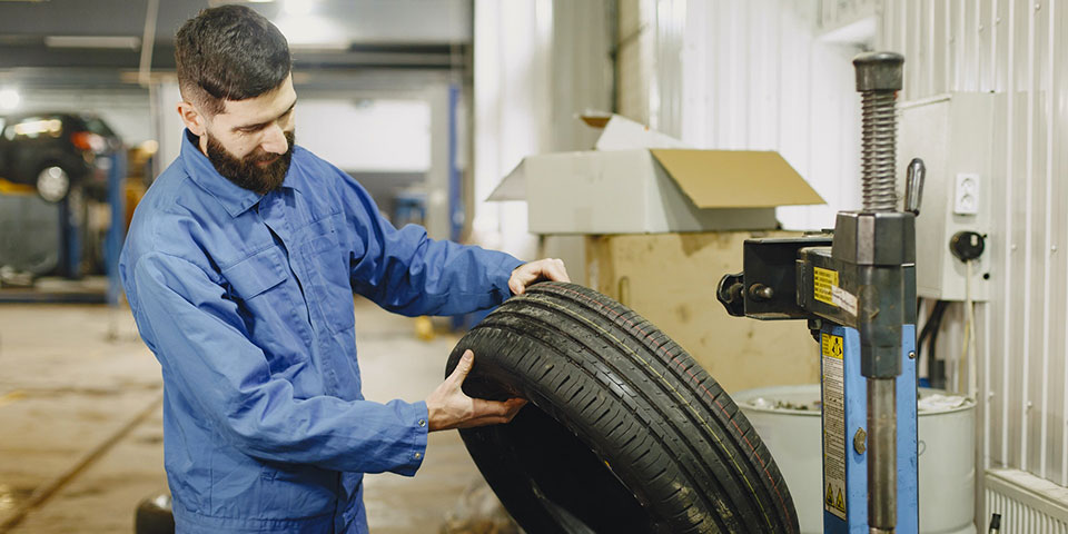 Garagiste inspecte l’état d’un pneu crevé pour réparation